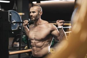 Bodybuilder during his workout with a barbell in the gym photo