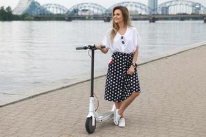 Stylish woman with electric scooter on the riverside photo