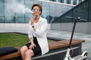 Young businesswoman smoking vape after her work photo