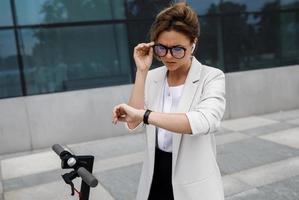 Young and beautiful businesswoman rides electric scooter photo