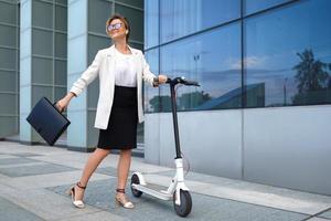 Young and beautiful businesswoman rides electric scooter photo