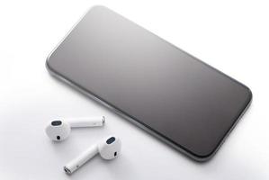 White wireless earphones and modern smart phone photo