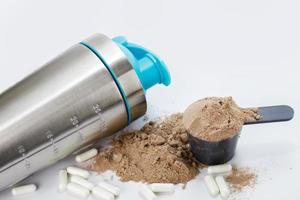 Shaker, scoop with protein powder and pills photo