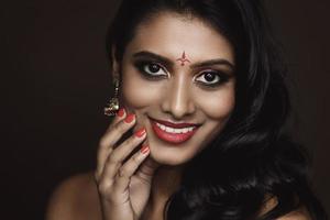 Portrait of Indian woman with beautiful makeup and hairstyle on brown background photo