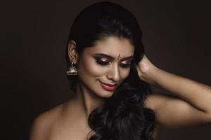 retrato de mujer india con hermoso maquillaje y peinado sobre fondo marrón foto