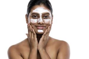 Young indian woman with a cleansing mask applied on her face photo