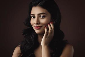 Indian woman with beautiful makeup and hairstyle on brown background photo