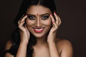 retrato de mujer india con hermoso maquillaje y peinado sobre fondo marrón foto