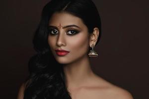 Portrait of Indian woman with beautiful makeup and hairstyle on brown background photo