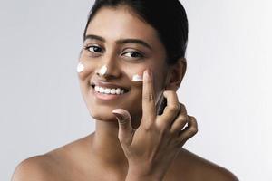 Beautiful Indian woman applying moisturizing cream on her face photo