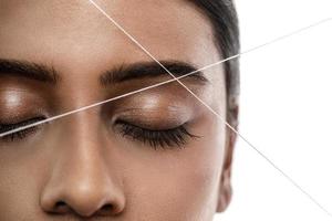 Eyebrow threading - epilation procedure for brow shape correction photo