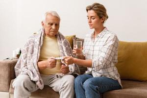 Woman is giving medicine to her sick elderly grandfather photo