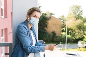 Woman with a prevention mask on her face is using smartphone photo