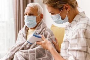 mujer cuidando a su anciano abuelo con síntomas de resfriado foto