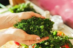 Female hands with chopped green dill and parsley photo