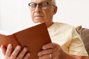 Wise and elderly man is reading book at home photo