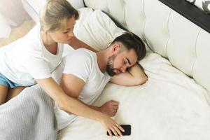 Cheating and mistrust concept. Jealous wife reads messages on her husband's phone. photo