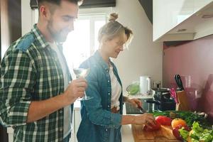 Happy couple cooking launch and drinking wine together in the kitchen photo