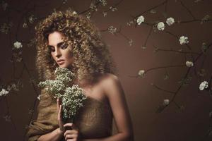 encantadora mujer joven con peinado afro y hermoso maquillaje con muchas flores blancas foto