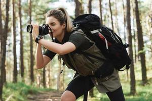 excursionista tomando fotos usando una cámara sin espejo moderna en un bosque verde