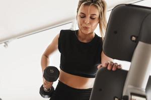 Athletic woman doing one arm dumbbell row exercise in the gym photo