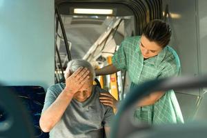 Young woman and senior man is feeling sick with migraine symptoms in public transport photo