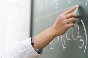 Scientist hand with a chalk writing a chemical equation photo