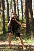 excursionista tomando fotos usando una cámara sin espejo moderna en un bosque verde