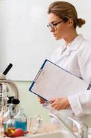 Woman scientist with a clipboard t in a laboratory during research photo