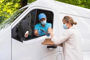 Safe delivery - courier on a van brings a pizza to the client photo