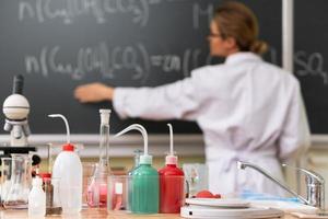 Teacher explaining how to read a chemical equation on a chalkboard during a chemistry lesson photo