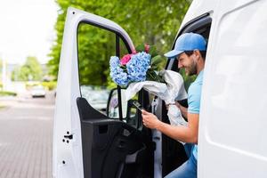 mensajero feliz con una tableta durante la entrega de flores foto