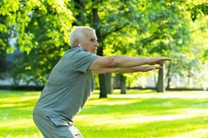 Elderly man exercising in green city park during his fitness workout photo