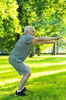 Elderly man exercising in green city park during his fitness workout photo