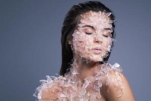 Female face covered with a lot small pieces of glass or ice photo