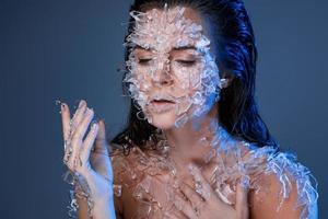 Female face covered with a lot small pieces of glass or ice photo