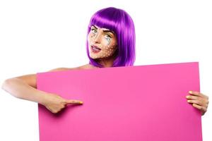 Model in creative image with pop art makeup is holding pink blank board photo