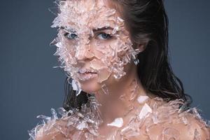 Female face covered with a lot small pieces of glass or ice photo