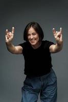 Middle aged woman wearing black t-shirt showing sign of the horns photo