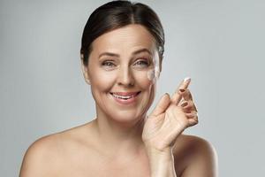 Middle aged woman applying anti-aging cream on her face photo