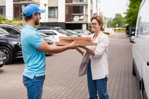 Delivery man wearing blue uniform delivers pizza to a woman client photo