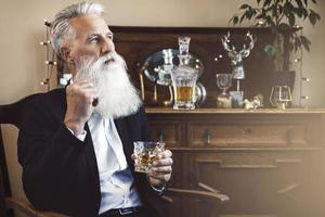 Handsome bearded senior man with a glass of whiskey photo