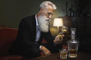 Handsome bearded senior man is looking at hourglass photo