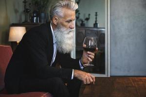 Handsome bearded senior man drinking red wine photo