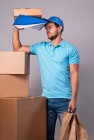 Tired delivery man during work with a packages in a cardboard boxes photo