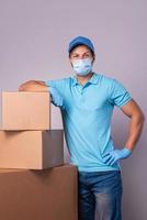 Young delivery man is wearing prevention mask and gloves with a cardboard boxes photo