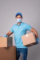 Young delivery man is wearing prevention mask and gloves with a cardboard boxes photo