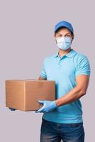 Young delivery man is wearing prevention mask and gloves with a cardboard boxes photo