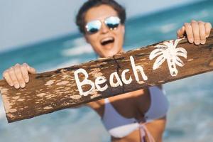 Happy wearing swimsuit with old wooden sign on the beach photo