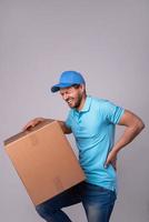 Delivery man suffering from a back pain while carrying heavy box photo